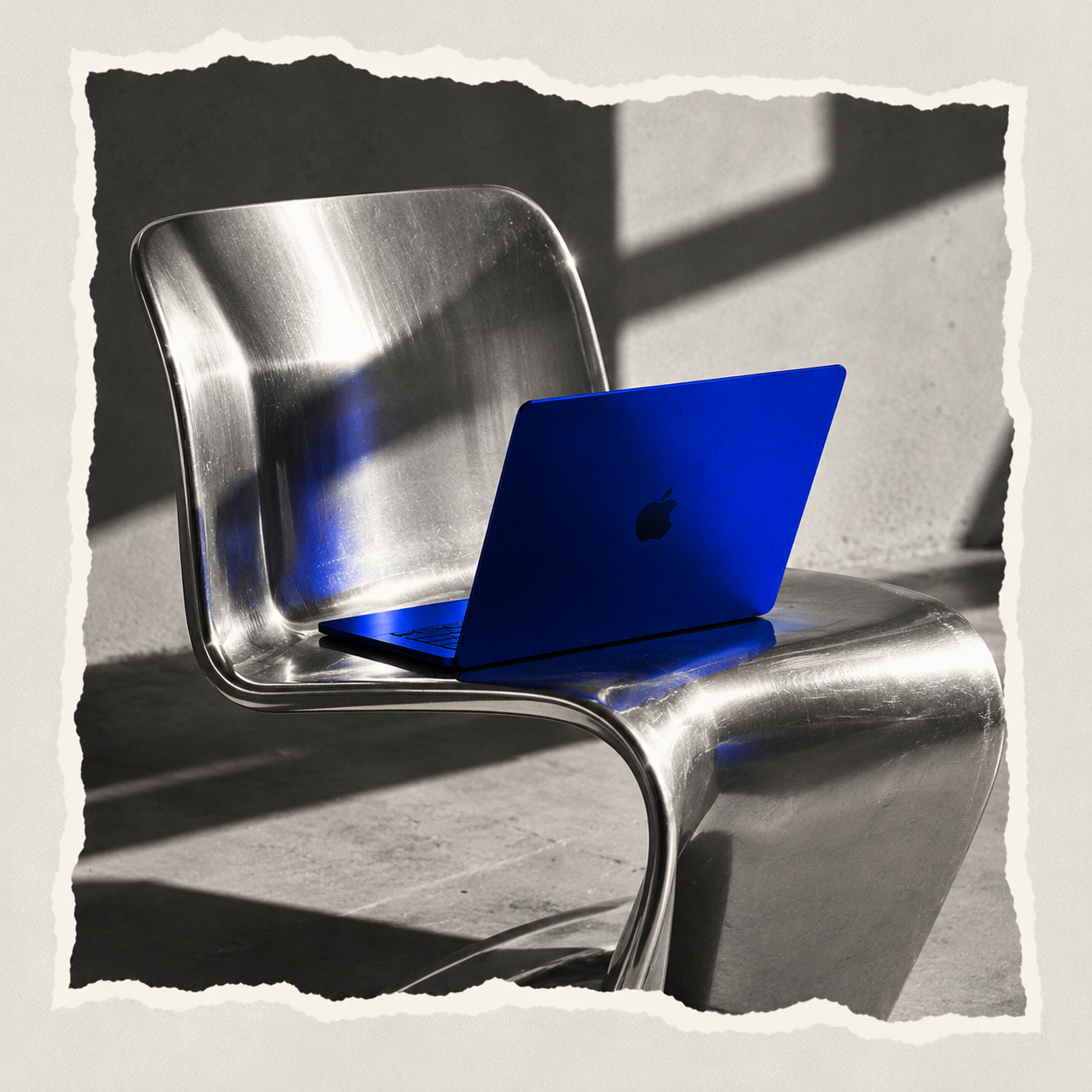 Blue laptop on a metal chair, sunlight across a concrete floor